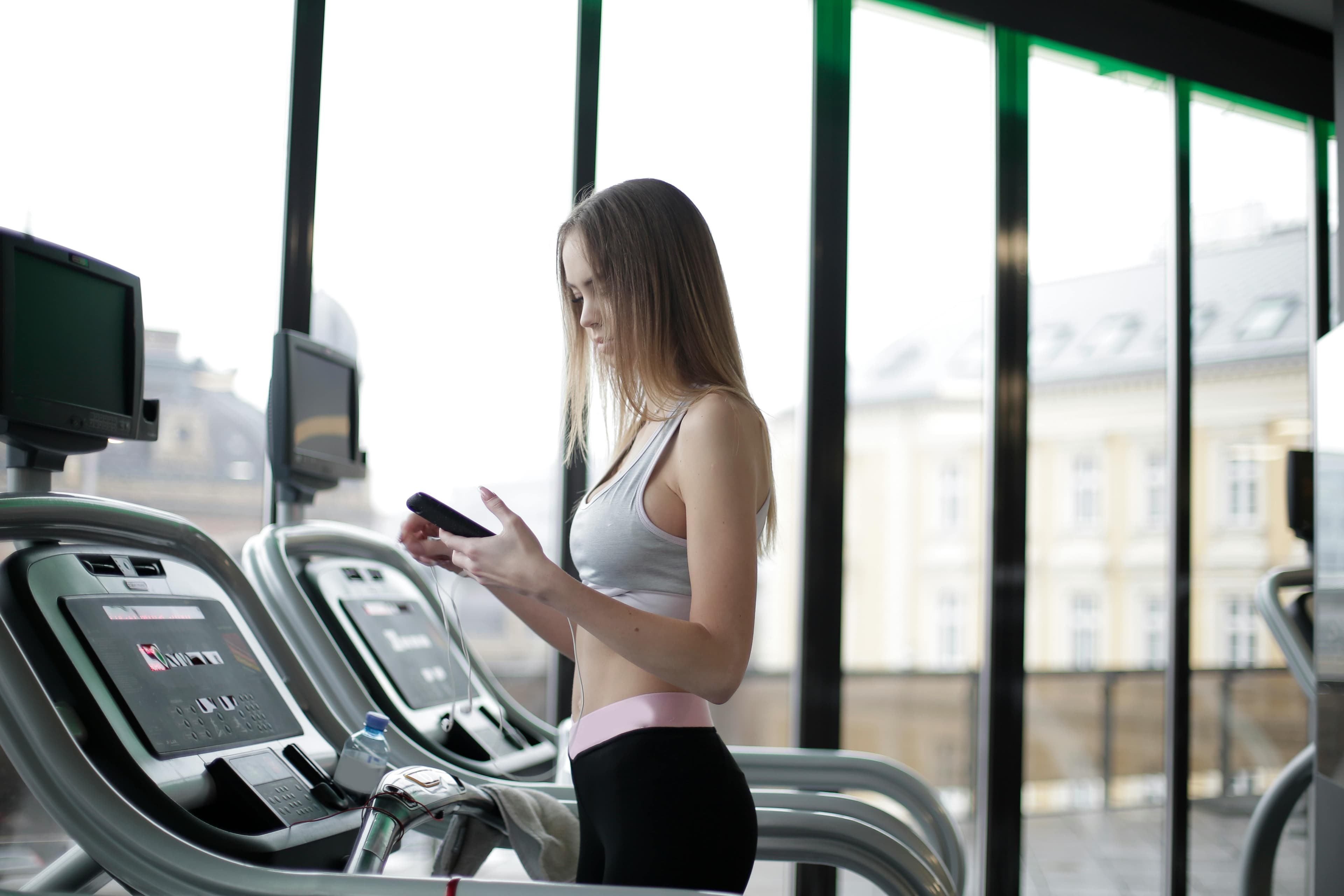 Athlete using a phone while training on a treadmill